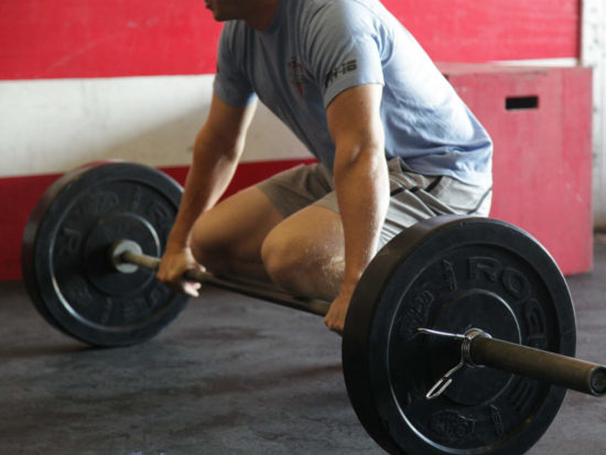 crossfit athlete coach lifting barbel in gym